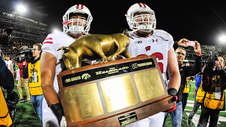 Sep 22, 2018; Iowa City, IA, USA; Wisconsin Badgers offensive lineman Beau Benzschawel (66) and fullback Alec Ingold (45) carry the Heartland Trophy after defeating the Iowa Hawkeyes at Kinnick Stadium. Mandatory Credit: Jeffrey Becker-Imagn Images