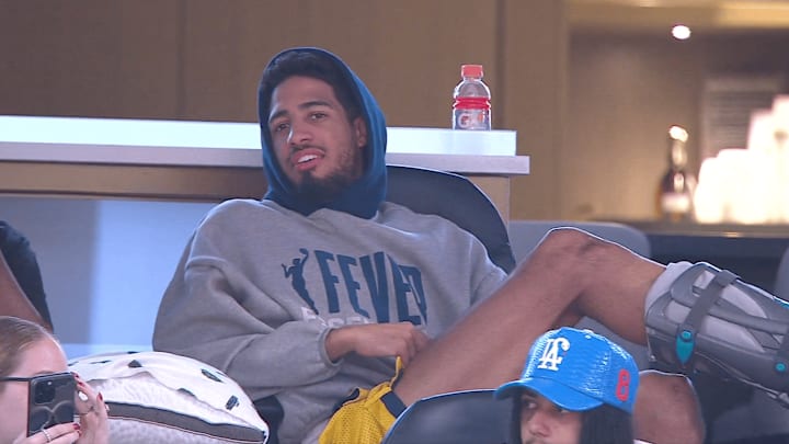 Haliburton watches on at the Indiana Fever game while wearing a leg boot