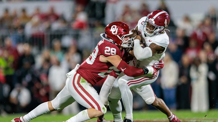 Nov 23, 2024; Norman, Oklahoma, USA; Alabama Crimson Tide quarterback Jalen Milroe (4) is tackled by Oklahoma Sooners linebacker Danny Stutsman (28) during the first quarter at Gaylord Family-Oklahoma Memorial Stadium. Mandatory Credit: William Purnell-Imagn Images