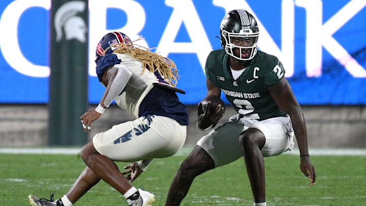 Aug 30, 2024; East Lansing, Michigan, USA;  Michigan State Spartans quarterback Aidan Chiles (2) evades Florida Atlantic Owls safety CJ Heard (1) in the third quarter at Spartan Stadium. Mandatory Credit: Dale Young-USA TODAY Sports