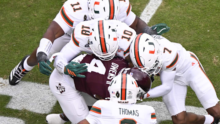 Dec 20, 2025; College Station, TX, USA; Texas A&M Aggies running back Rueben Owens II (4) is tackled by Miami Hurricanes defensive lineman David Blay (11), linebacker Jr. Raul Aguirre (10), safety Zechariah Poyser (7), and defensive back Jakobe Thomas (8) during first quarter of the first round game of the CFP National Playoff at Kyle Field. Mandatory Credit: Jerome Miron-Imagn Images