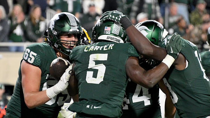 Oct 19, 2024; East Lansing, Michigan, USA;  Michigan State Spartans running back Nate Carter (5) celebrates his fourth quarter touchdown against the Iowa Hawkeyes with his teammates at Spartan Stadium. Mandatory Credit: Dale Young-Imagn Images