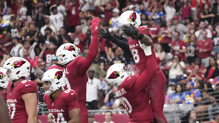Arizona Cardinals offensive tackle Paris Johnson Jr. (70) lifts wide receiver Marvin Harrison Jr. (18) after a touchdown catch against the Los Angeles Rams during the first quarter at State Farm Stadium.