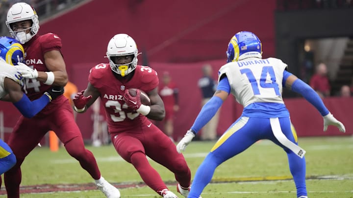 Arizona Cardinals running back Trey Benson (33) runs through a hole against Los Angeles Rams cornerback Cobie Durant (14) during the second quarter at State Farm Stadium.