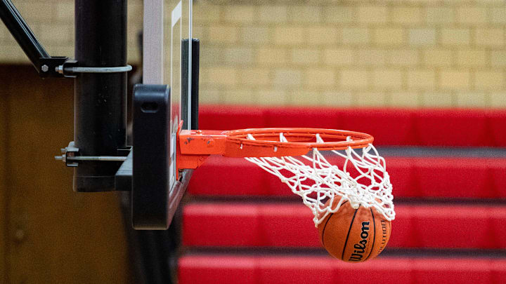 A basketball drops through the net at a high school basketball game. 