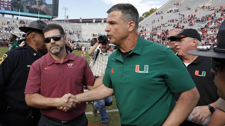 Oct 15, 2022; Blacksburg, Virginia, USA;  Virginia Tech Hokies head coach Brent Pry (left) and Miami Hurricanes head coach Mario Cristobal shake hands near mid field after the game at Lane Stadium. Mandatory Credit: Reinhold Matay-Imagn Images