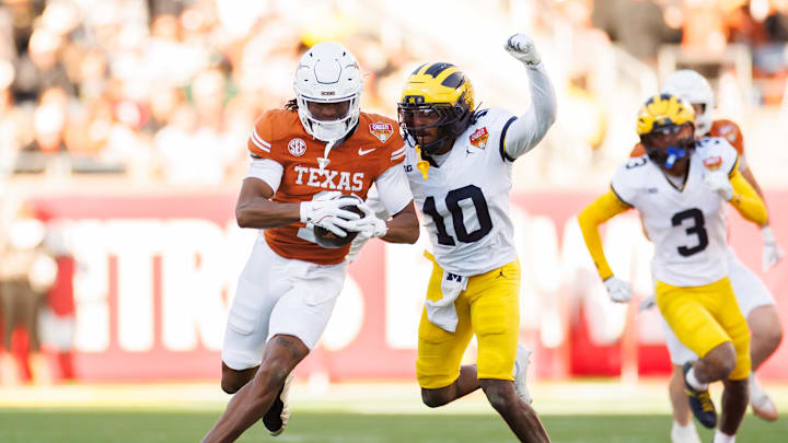 Dec 31, 2025; Orlando, FL, USA; Texas Longhorns wide receiver Ryan Wingo (1) runs with the ball while Michigan Wolverines defensive back Zeke Berry (10) attempts to tackle during the first half at Camping World Stadium. Mandatory Credit: Matt Pendleton-Imagn Images