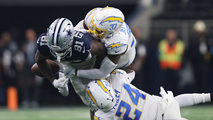 Aug 24, 2024; Arlington, Texas, USA; Dallas Cowboys tight end John Stephens Jr. (81) fumbles the ball after being tackled by Los Angeles Chargers safety Thomas Harper (37) and safety AJ Finley (24) in the second quarter at AT&T Stadium. Mandatory Credit: Tim Heitman-Imagn Images
