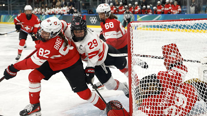 Feb 7, 2026; Milan, Italy; Marie-Philip Poulin (29) of Canada reaches for the puck between Saskia Maurer (29) of Switzerland and Alessia Baechler (82) of Switzerland in women's ice hockey group A play during the Milano Cortina 2026 Olympic Winter Games at Milano Rho Ice Hockey Arena. Mandatory Credit: Geoff Burke-Imagn Images