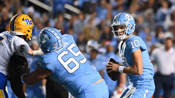 Oct 29, 2022; Chapel Hill, North Carolina, USA; North Carolina Tar Heels quarterback Drake Maye (10)*looks to pass as offensive lineman Corey Gaynor (65) blocks Pittsburgh Panthers defensive lineman Deslin Alexandre (5) pressures in the first quarter at Kenan Memorial Stadium. Mandatory Credit: Bob Donnan-Imagn Images