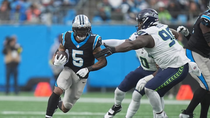 Dec 28, 2025; Charlotte, North Carolina, USA; Carolina Panthers running back Rico Dowdle (5) runs the ball against Seattle Seahawks defensive tackle Jarran Reed (90) during the third quarter at Bank of America Stadium. Mandatory Credit: Jim Dedmon-Imagn Images