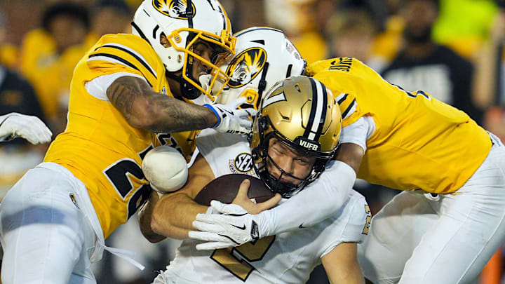 Sep 21, 2024; Columbia, Missouri, USA; Vanderbilt Commodores quarterback Diego Pavia (2) is tackled by Missouri Tigers safety Joseph Charleston (28) and safety Marvin Burks Jr. (1) during overtime at Faurot Field at Memorial Stadium. Mandatory Credit: Jay Biggerstaff-Imagn Images