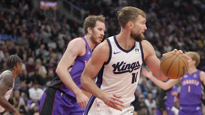 Nov 2, 2024; Toronto, Ontario, CAN; Sacramento Kings forward Domantas Sabonis (11) gets control of a rebound as Toronto Raptors center Jakob Poeltl (19) pursues during the first half at Scotiabank Arena. Mandatory Credit: John E. Sokolowski-Imagn Images