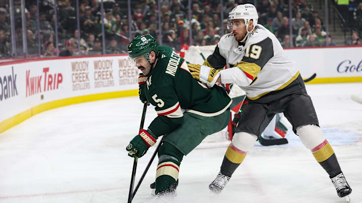 Mar 25, 2025; Saint Paul, Minnesota, USA; Minnesota Wild defenseman Jake Middleton (5) and Vegas Golden Knights right wing Reilly Smith (19) compete for the puck during the first period at Xcel Energy Center. Mandatory Credit: Matt Krohn-Imagn Images