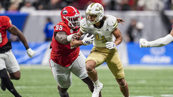 Nov 28, 2025; Atlanta, Georgia, USA; Georgia Tech Yellow Jackets wide receiver Isiah Canion (4) runs against Georgia Bulldogs defensive lineman Nnamdi Ogboko (95) during the second half at Mercedes-Benz Stadium. Mandatory Credit: Dale Zanine-Imagn Images