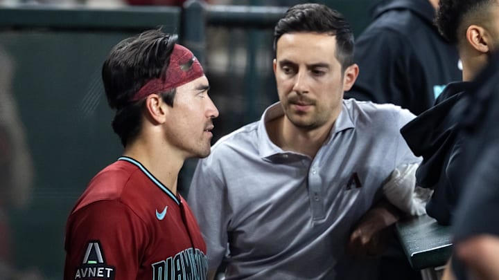 Apr 19, 2026; Phoenix, Arizona, USA; Arizona Diamondbacks outfielder Corbin Carroll (left) talks with a team trainer in the dugout in the fourth inning against the Toronto Blue Jays at Chase Field. Mandatory Credit: Mark J. Rebilas-Imagn Images