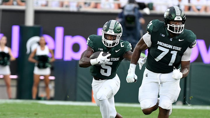 Aug 30, 2024; East Lansing, Michigan, USA;  Michigan State Spartans running back Nate Carter (5) follows blocker Michigan State Spartans offensive lineman Kristian Phillips (71) during the game against the Florida Atlantic Owls at Spartan Stadium. Mandatory Credit: Dale Young-Imagn Images