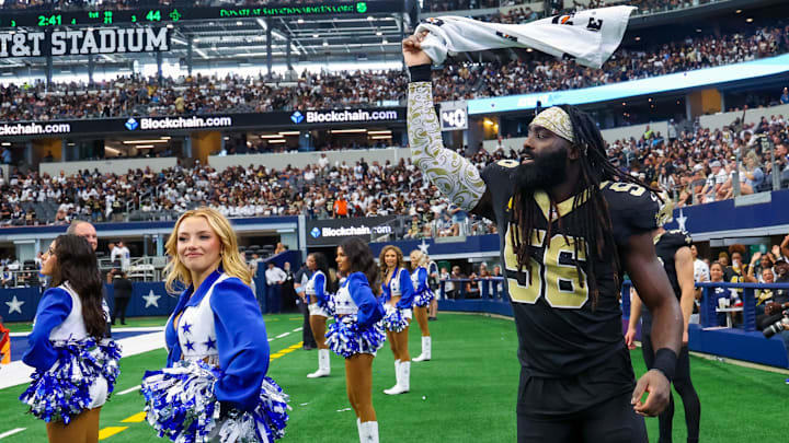 Sep 15, 2024; Arlington, Texas, USA;  New Orleans Saints linebacker Demario Davis (56) waves a towel in front of a Dallas Cowboys cheerleader during the fourth quarter at AT&T Stadium. Mandatory Credit: Kevin Jairaj-Imagn Images
