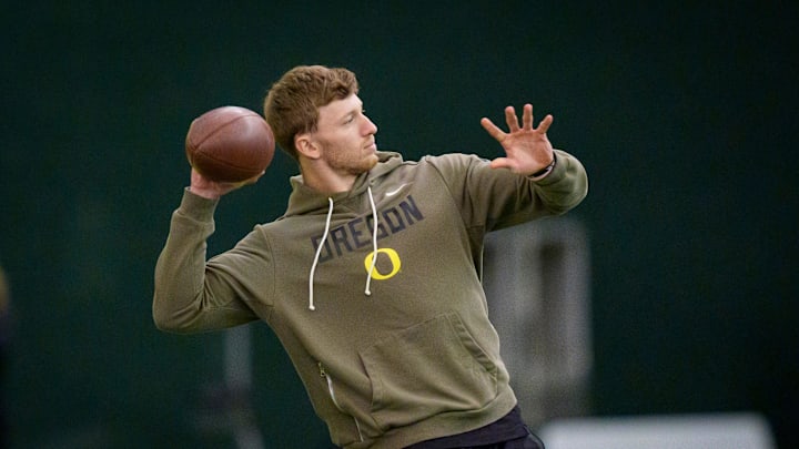 Oregon defensive back Dillon Thieneman helps inside linebacker Bryce Boettcher warm up