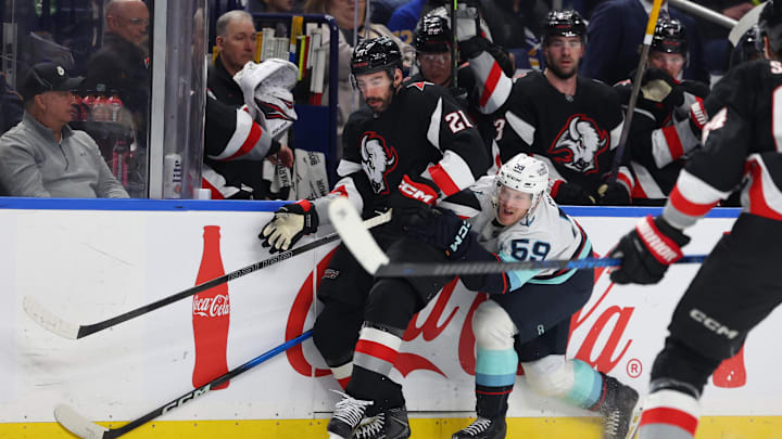 Mar 28, 2026; Buffalo, New York, USA;  Buffalo Sabres defenseman Conor Timmins (21) and Seattle Kraken center Ben Meyers (59) go after a loose puck during the first period at KeyBank Center. Mandatory Credit: Timothy T. Ludwig-Imagn Images