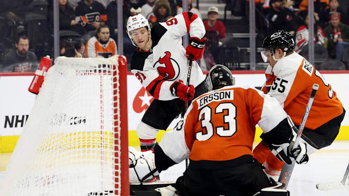 Dawson Mercer (Devils #91) tries to sneak a shot past Samuel Ersson (Flyers #33) and Rasmus Ristolainen (Flyers #55)