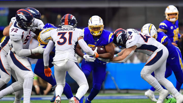 Dec 10, 2023; Inglewood, California, USA; Los Angeles Chargers running back Joshua Kelley (25) runs the ball against Denver Broncos linebacker Josey Jewell (47) and safety Justin Simmons (31) during the first half at SoFi Stadium. Mandatory Credit: Gary A. Vasquez-USA TODAY Sports