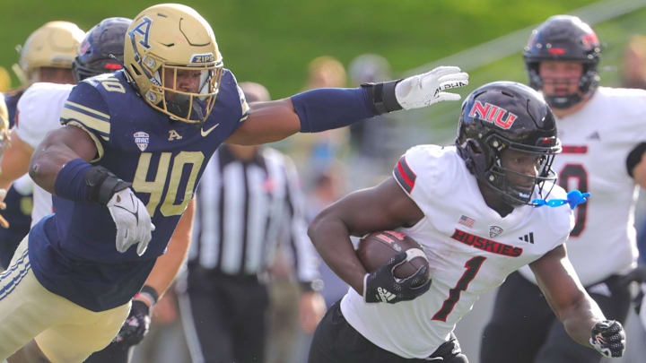 NIU running back Antario Brown gets past University of Akron linebacker Bryan McCoy, top, and defensive back Corey Thomas, Jr. on Saturday, Oct. 7, 2023, in Akron, Ohio, at InfoCision Stadium. [Phil Masturzo/ Beacon Journal]