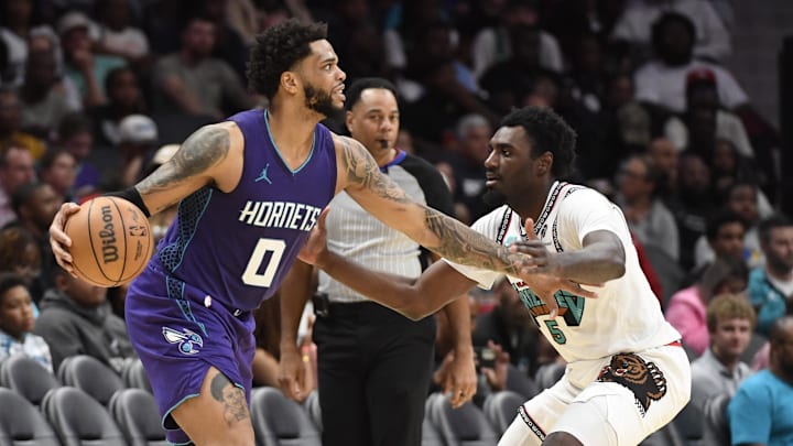 Apr 8, 2025; Charlotte, North Carolina, USA;  Charlotte Hornets forward Miles Bridges (0) looks to pass as he is defended by Memphis Grizzlies guard forward Vince Williams Jr. (5) during the second half at the Spectrum Center. Mandatory Credit: Sam Sharpe-Imagn Images