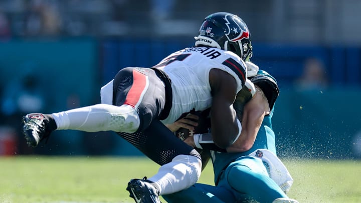 Dec 1, 2024; Jacksonville, Florida, USA; Jacksonville Jaguars quarterback Trevor Lawrence (16) is hit by Houston Texans linebacker Azeez Al-Shaair (0) as he slides  down in the second quarter in the second quarter at EverBank Stadium. Mandatory Credit: Nathan Ray Seebeck-Imagn Images