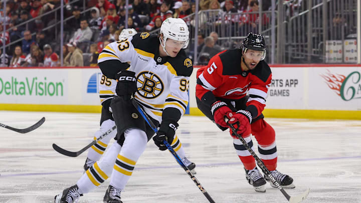 Apr 8, 2025; Newark, New Jersey, USA; Boston Bruins center Fraser Minten (93) skates with the puck as New Jersey Devils defenseman Brenden Dillon (5) defends during the third period at Prudential Center. Mandatory Credit: Ed Mulholland-Imagn Images