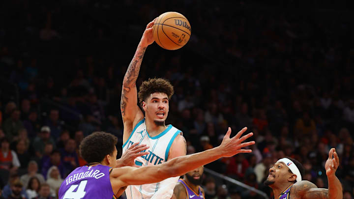 Jan 12, 2025; Phoenix, Arizona, USA; Charlotte Hornets guard LaMelo Ball (1) passes the ball past Phoenix Suns center Oso Ighodaro (4) during the second half at Footprint Center. Mandatory Credit: Mark J. Rebilas-Imagn Images