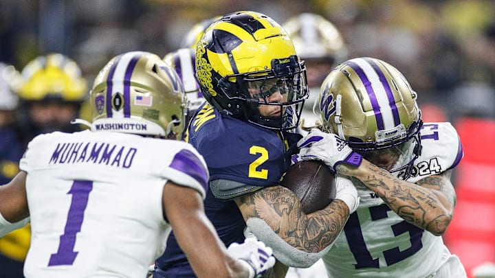 Michigan running back Blake Corum (2) runs against Washington cornerback Jabbar Muhammad (1) and cornerback Kamren Fabiculanan (13) during the first half of the national championship game at NRG Stadium in Houston on Monday, Jan. 8, 2024.