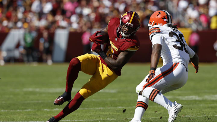 Oct 6, 2024; Landover, Maryland, USA; Washington Commanders running back Brian Robinson Jr. (8) carries the ball as Cleveland Browns linebacker Devin Bush (30) defends during the second quarter at NorthWest Stadium. Mandatory Credit: Geoff Burke-Imagn Images