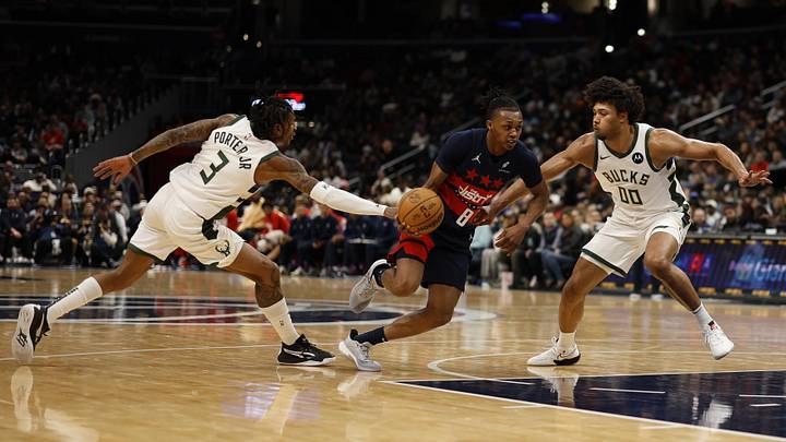 Feb 21, 2025; Washington, District of Columbia, USA; Washington Wizards guard Bub Carrington (8) drives to the basket as Milwaukee Bucks guard Kevin Porter Jr. (3) and Bucks center Jericho Sims (00) defend in the second half at Capital One Arena. Mandatory Credit: Geoff Burke-Imagn Images