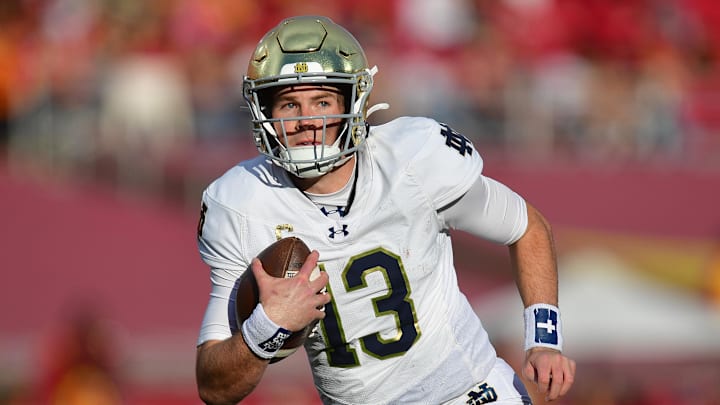 Nov 30, 2024; Los Angeles, California, USA; Notre Dame Fighting Irish quarterback Riley Leonard (13) runs the ball against the Southern California Trojans during the second half at the Los Angeles Memorial Coliseum. Mandatory Credit: Gary A. Vasquez-Imagn Images