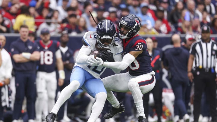 Dec 31, 2023; Houston, Texas, USA; Tennessee Titans wide receiver DeAndre Hopkins (10) makes a reception as Houston Texans safety DeAndre Houston-Carson (30) attempts to make a tackle during the first quarter at NRG Stadium. Mandatory Credit: Troy Taormina-USA TODAY Sports