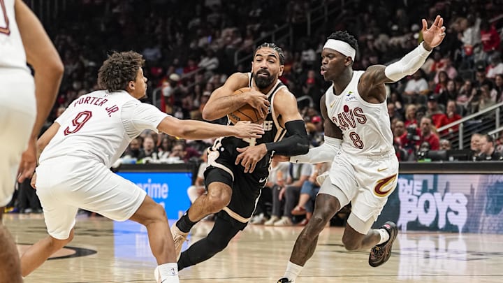 Apr 10, 2026; Atlanta, Georgia, USA; Atlanta Hawks guard Gabe Vincent (4) tries to go between Cleveland Cavaliers guards Craig Porter Jr. (9) and Dennis Schroder (8) during the first half at State Farm Arena. Mandatory Credit: Dale Zanine-Imagn Images
