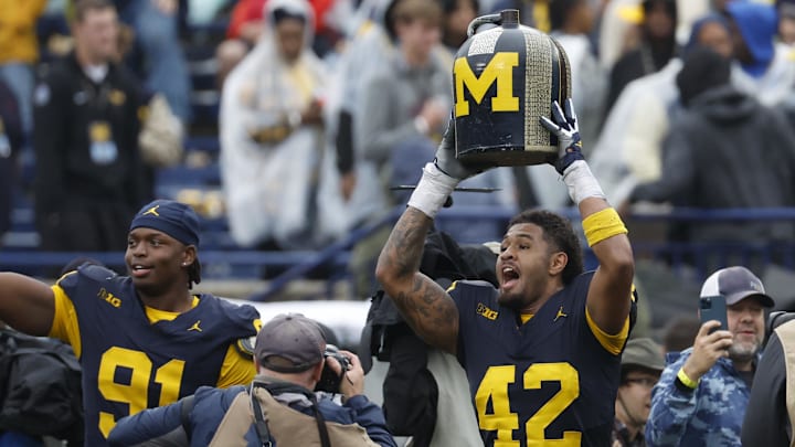Sep 28, 2024; Ann Arbor, Michigan, USA;  Michigan Wolverines defensive end TJ Guy (42) lefts up the Little Brown Jug after defeating the Minnesota Golden Gophers at Michigan Stadium. Mandatory Credit: Rick Osentoski-Imagn Images