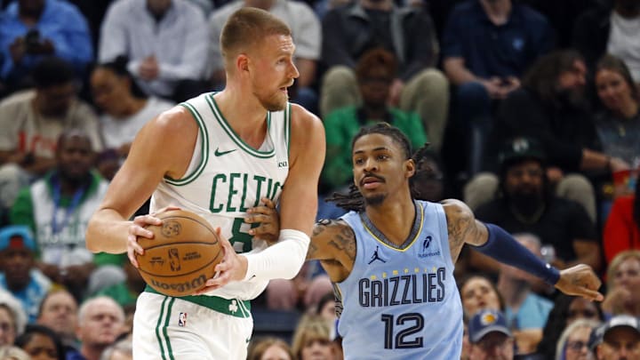 Mar 31, 2025; Memphis, Tennessee, USA; Boston Celtics center Kristaps Porzingis (8) handles the ball as Memphis Grizzlies guard Ja Morant (12) defends during the fourth quarter at FedExForum. Mandatory Credit: Petre Thomas-Imagn Images