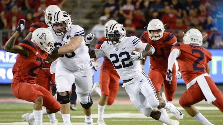 Sep 1, 2018; Tucson, AZ, USA; Brigham Young Cougars running back Squally Canada (22) runs the ball under pressure from Arizona Wildcats defensive end Kylan Wilborn (14) and cornerback Lorenzo Burns (2) during the first half at Arizona Stadium. Mandatory Credit: Casey Sapio-Imagn Images