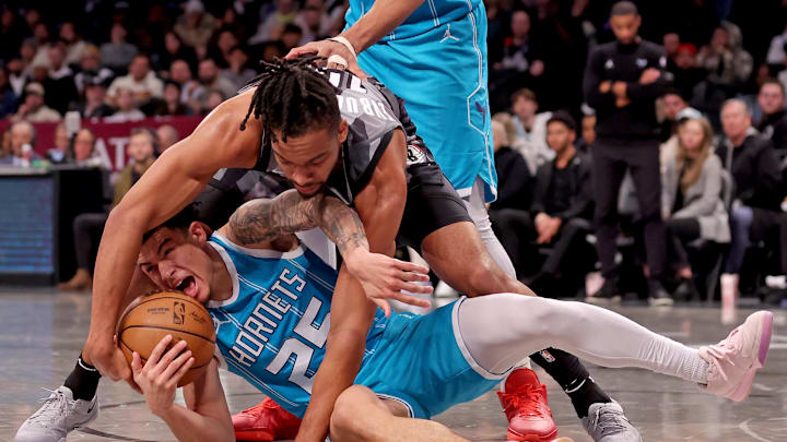 Feb 10, 2025; Brooklyn, New York, USA; Brooklyn Nets forward Tosan Evbuomwan (12) and Charlotte Hornets guard KJ Simpson (25) fight for the ball during the fourth quarter at Barclays Center. Mandatory Credit: Brad Penner-Imagn Images