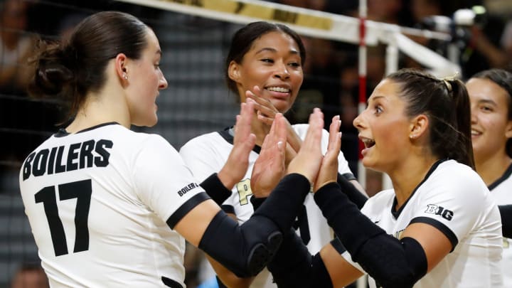Eva Hudson, Lourdes Myers and Chloe Chicoine celebrate during a volleyball game