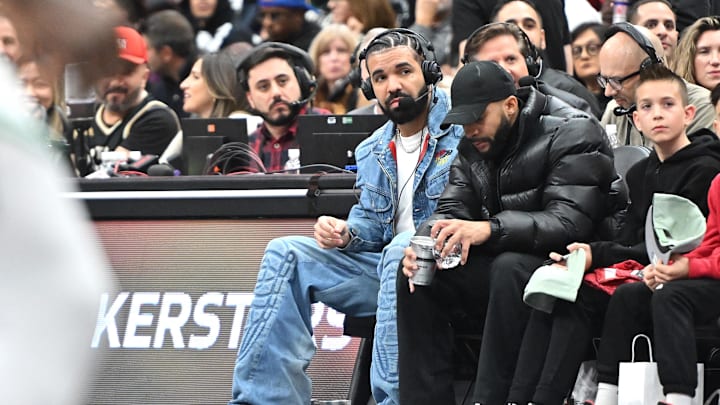Nov 17, 2023; Toronto, Ontario, CAN;  Recording artist Drake wears headphones to conduct an in-game media interview while watching the Toronto Raptors host the Boston Celtics at Scotiabank Arena. Mandatory Credit: Dan Hamilton-Imagn Images