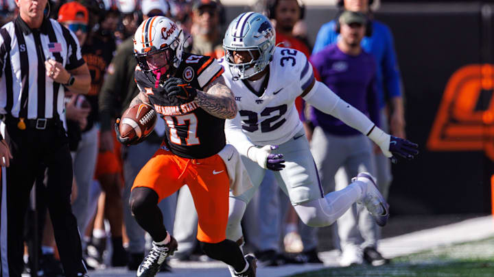 Nov 15, 2025; Stillwater, Oklahoma, USA; Oklahoma State Cowboys wide receiver Gavin Freeman (17) runs the ball around Kansas State Wildcats linebacker Des Purnell (32) during the first half at Boone Pickens Stadium. Mandatory Credit: William Purnell-Imagn Images