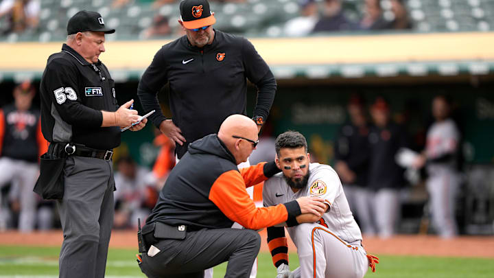 Baltimore Orioles v Oakland Athletics: Athletic trainer Brian Ebel checks on an injured player