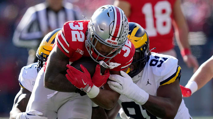 Ohio State Buckeyes running back TreVeyon Henderson (32) gets tackled by Michigan Wolverines defensive end Cameron Brandt (91) during the first quarter of the NCAA football game at Ohio Stadium in Columbus on Saturday, Nov. 30, 2024.