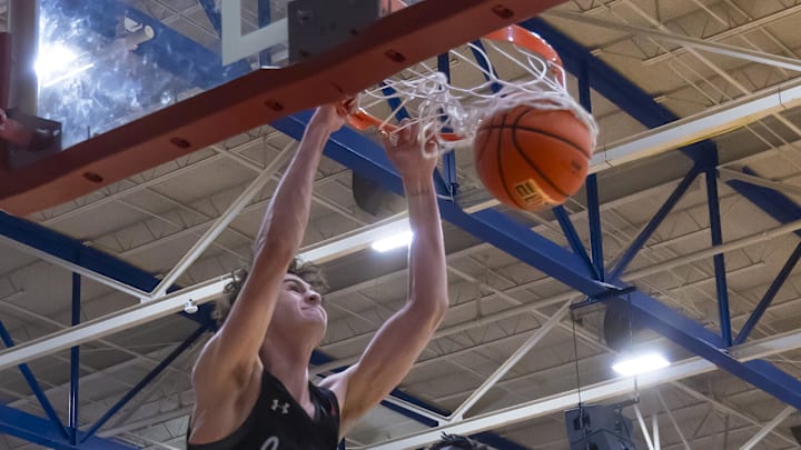 Lake Travis Cavaliers forward Hudson Greer (10) slam dunks and hangs on the rim as Westlake Chaparrals center Wonder Kahozi (35) looks on during the second period at the District 26-6A boys basketball game on Tuesday, Dec 5, 2023, at Westlake High School     West Lake Hills, TX.