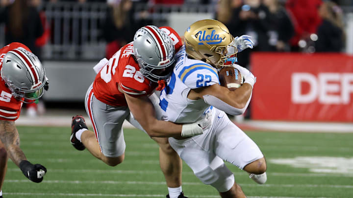 Nov 15, 2025; Columbus, Ohio, USA;  UCLA Bruins running back Anthony Frias II (22) runs the ball as Ohio State Buckeyes safety Leroy Roker (28) makes the tackle during the third quarter at Ohio Stadium. Mandatory Credit: Joseph Maiorana-Imagn Images