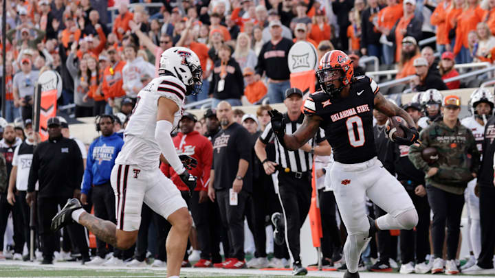 Oklahoma State's Ollie Gordon II runs the ball against Texas Tech's C.J. Baskerville during an NCAA football game on Saturday, Nov. 23, 2024, in Stillwater, Okla.