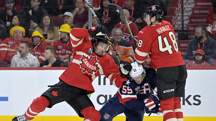 Feb 15, 2025; Montreal, Quebec, CAN; [Imagn Images direct customers only] Team Canada forward Mark Stone (61) and teammate Team Canada defenseman Thomas Harley (48) check Team United States forward Jake Guentzel (59) in the third period during a 4 Nations Face-Off ice hockey game at the Bell Centre. Mandatory Credit: Eric Bolte-Imagn Images